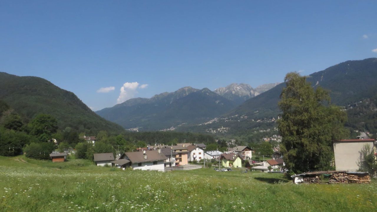 Cui Dariolo – Malesco in Italy - a green field with houses and mountains in the background.