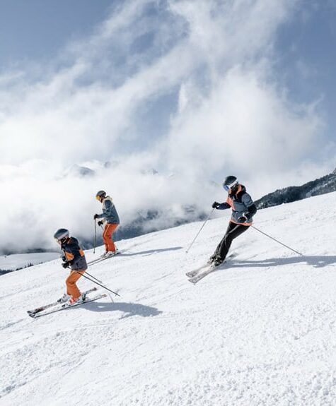 A family enjoying skiing in Aussois, Savoie Mont Blanc, with a charming chalet in the background. This picturesque scene captures the excitement and fun of winter sports in the French Alps.