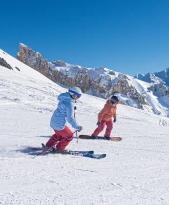 A skier glides down a slope in Aussois, Savoie Mont Blanc, a popular ski resort in France. Surrounding the winter sports scene are charming chalets blanketed in snow.