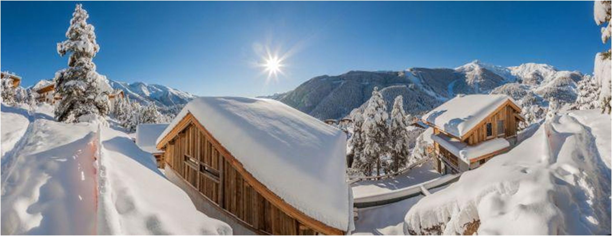 La Pesse in France - a wooden cabin in the snow with mountains in the background.
