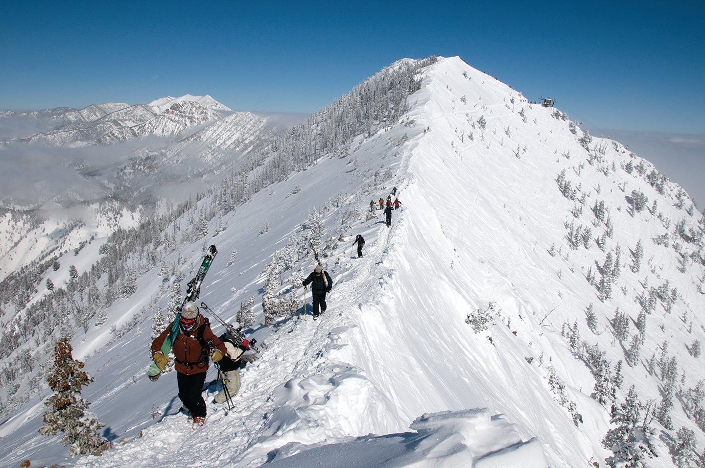 Bridger Bowl – Bozeman in USA - a group of people climbing up a snowy mountain.
