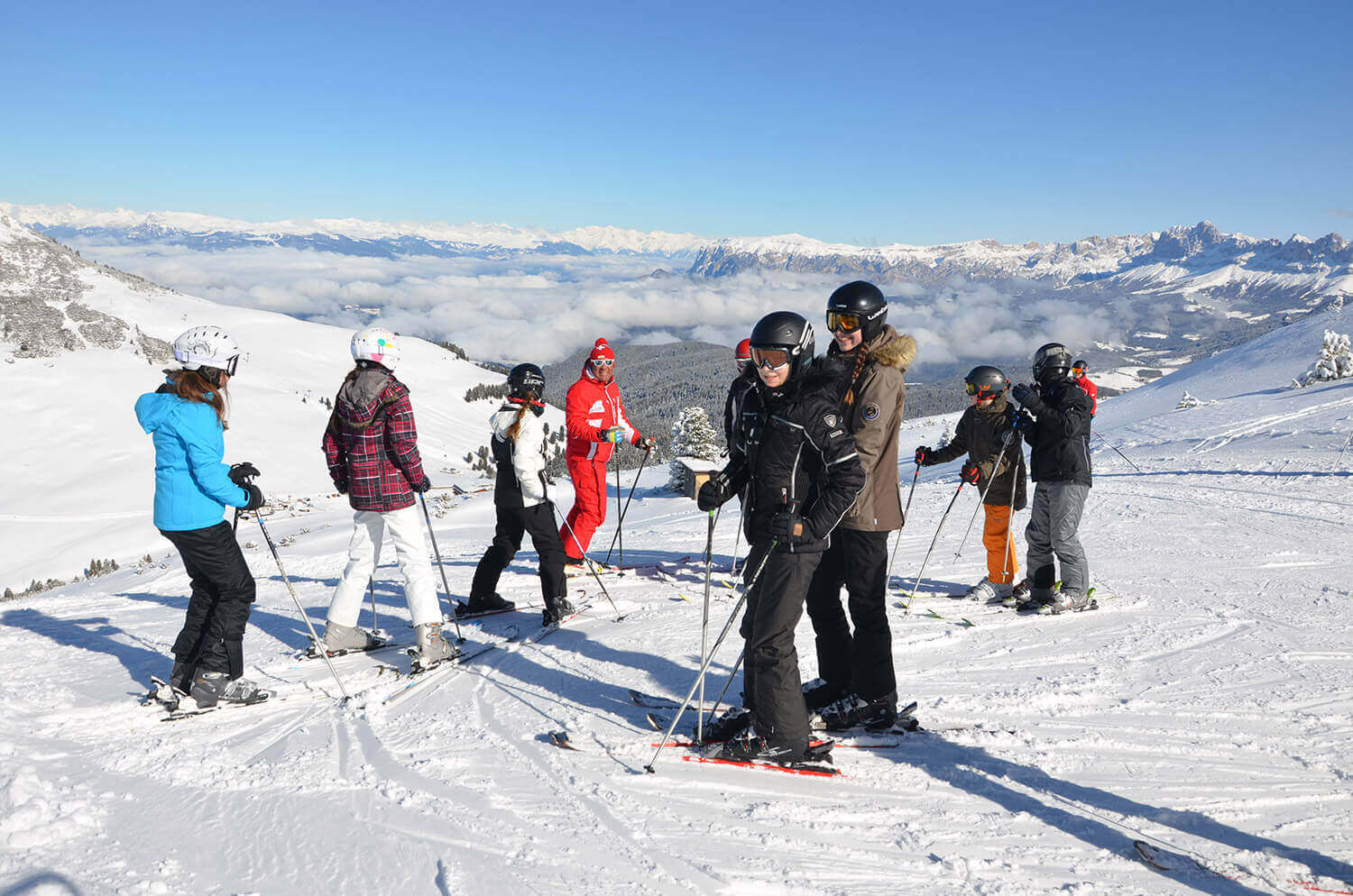 A lively winter sports scene at the Jochgrimm ski resort in South Tyrol Italy featuring a cozy chalet and groups of people including a family engaging in skiing activities.
