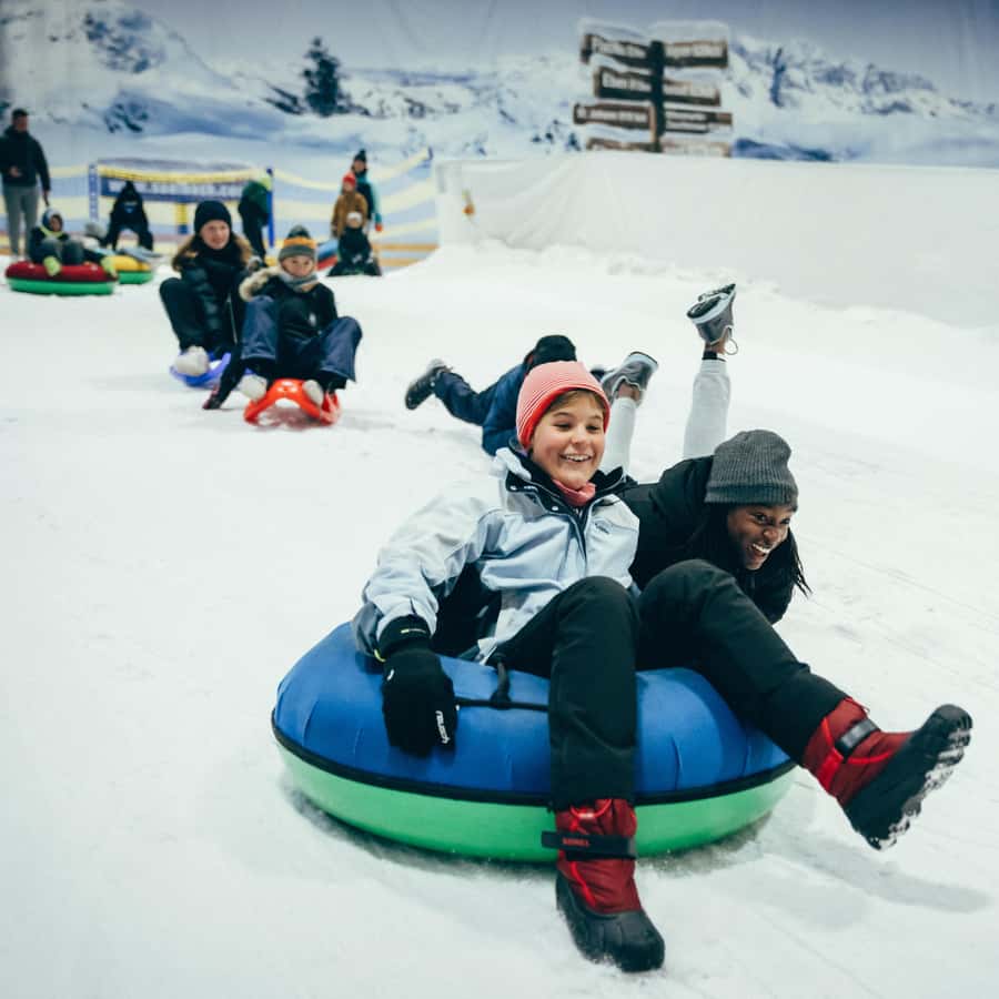 Alpenpark Neuss in Germany - two children sled down a hill on a sled sler.