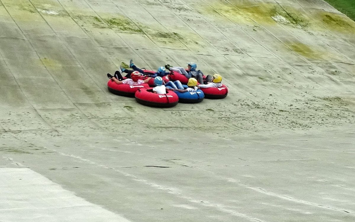 Halifax Ski Centre in United Kingdom - a group of people are tubling down a hill.