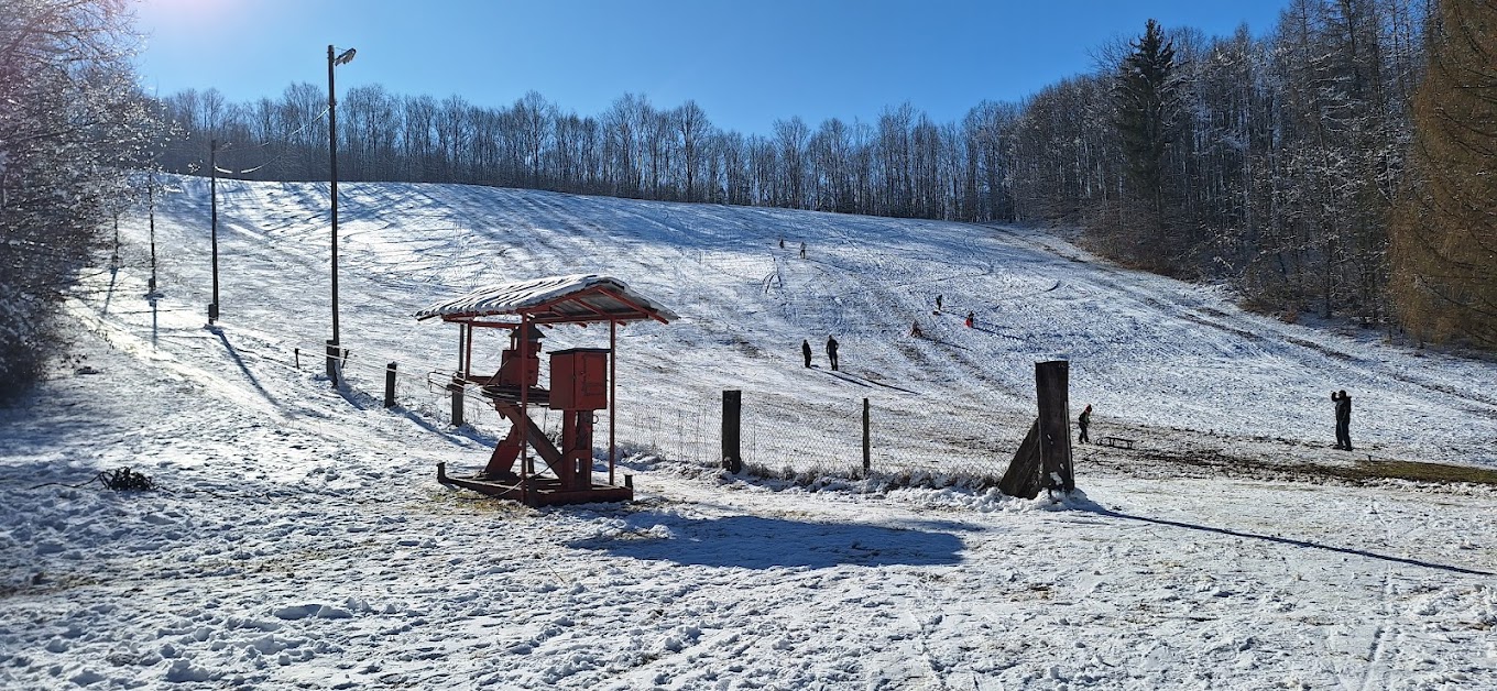 Skijalište Tominac in Croatia - a snow covered ski slope with a red cabin on it.