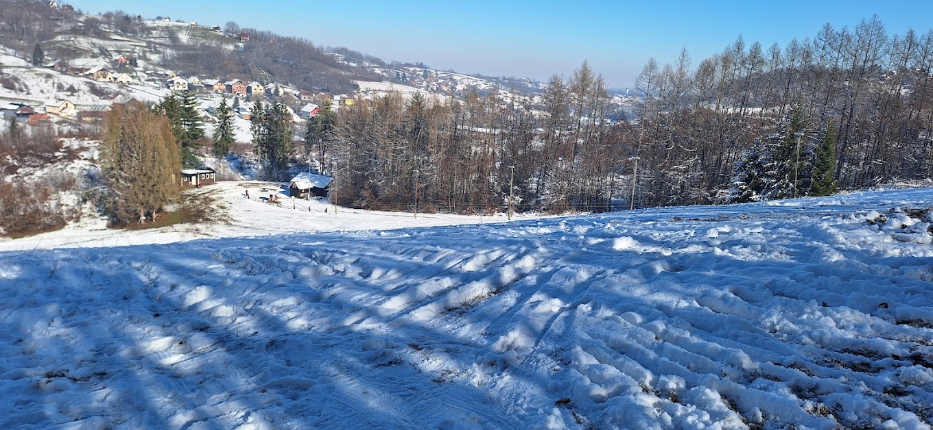 Skijalište Tominac in Croatia: a snow covered hill with trees and buildings in the background.