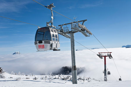 A breathtaking view from Feuerkogel-Ebensee in Austria. It features a ski lift, a quaint chalet, and a ski resort enveloped in stunning winter scenery, presenting an idyllic winter sports scene.