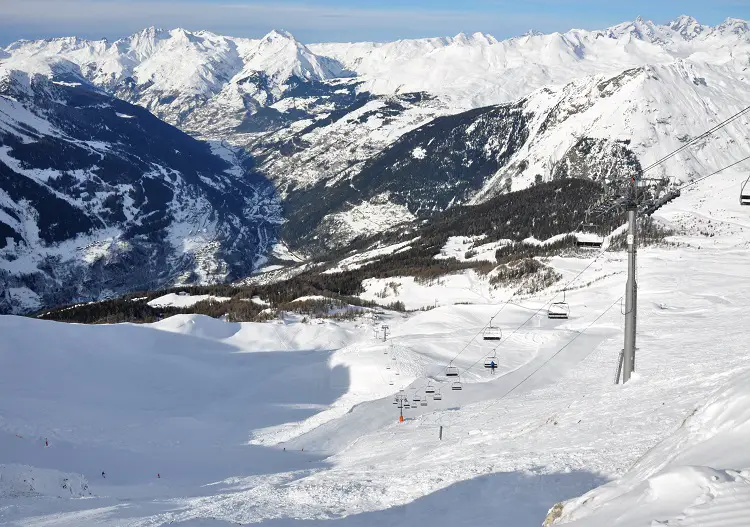 A scenic view of the Sainte Foy ski resort in France, featuring a charming chalet, skiers on the slopes, and a bustling winter sports centre.