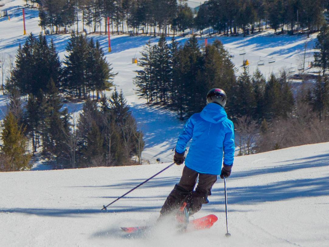 Hunter Mountain in USA - a person in blue jacket skiing down a hill.