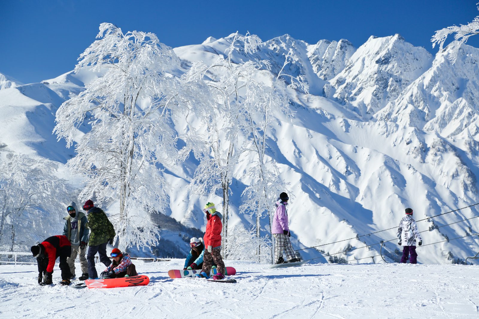 Hakuba Iwatake Mountain Resort in Japan - a group of people standing on top of a snow covered mountain.