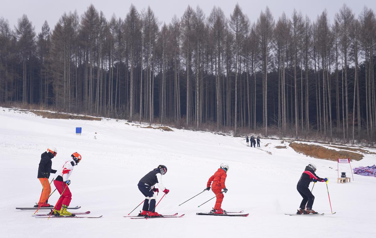 Wanfeng – Tonghua in China - a group of people skiing down a snow covered hill.