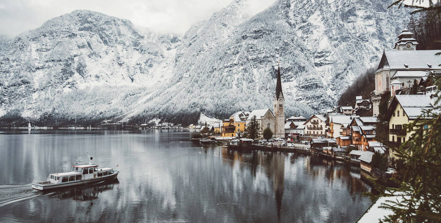 Hallstatt in Austria - a boat in the middle of a lake surrounded by mountains.
