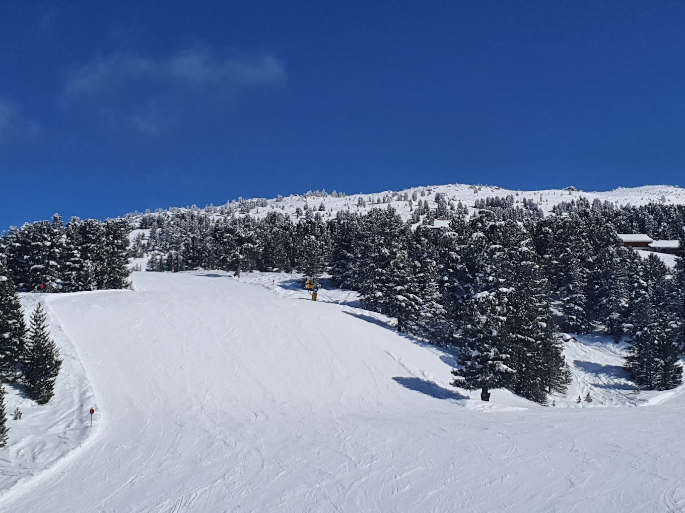 Glungezerbahn in Austria - a snow covered ski slope with trees in the background.
