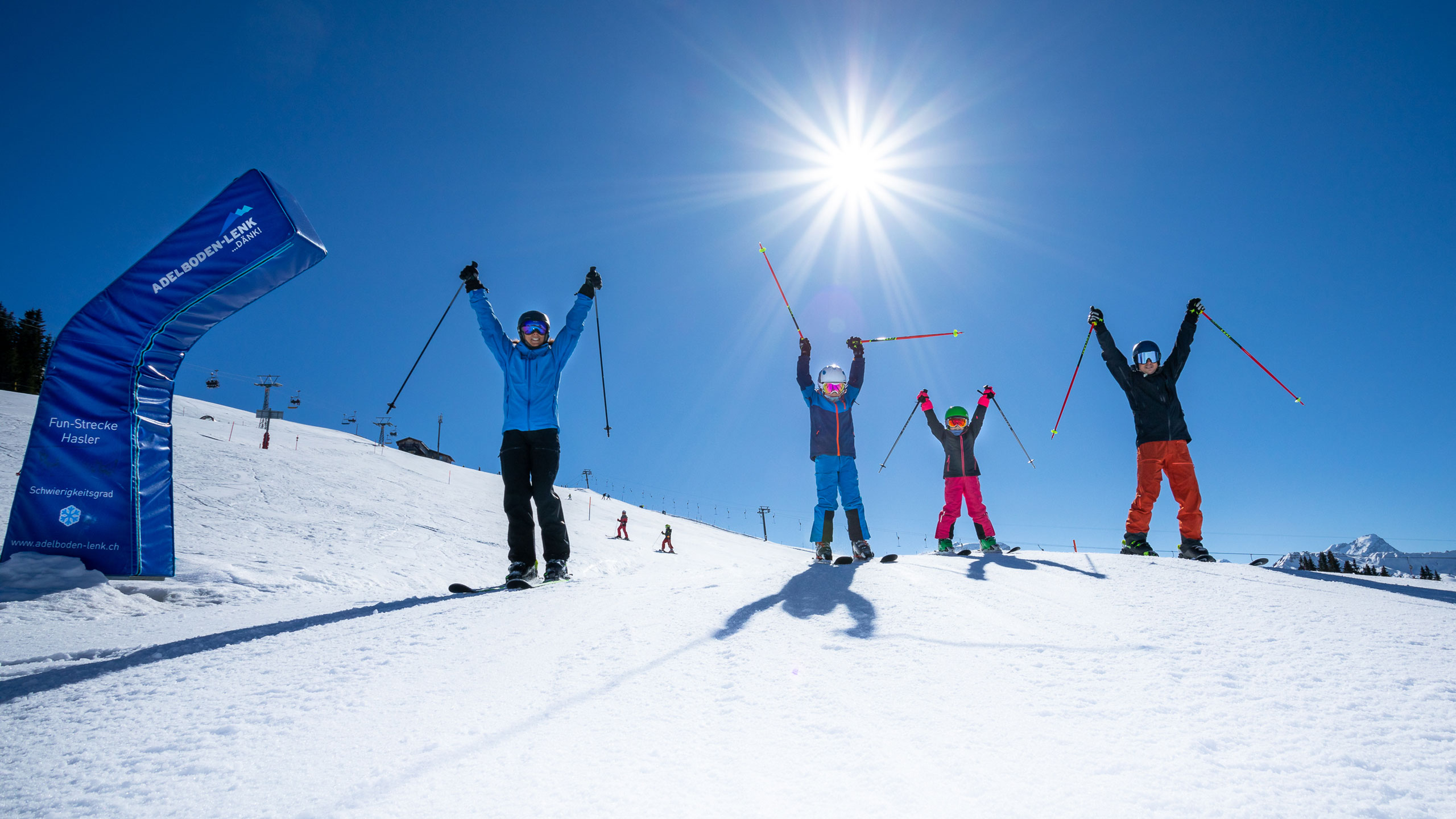 Winter sports scene at Betelberg in Switzerland, featuring a family and group of people skiing on the beautifully snowy ski resort slopes.