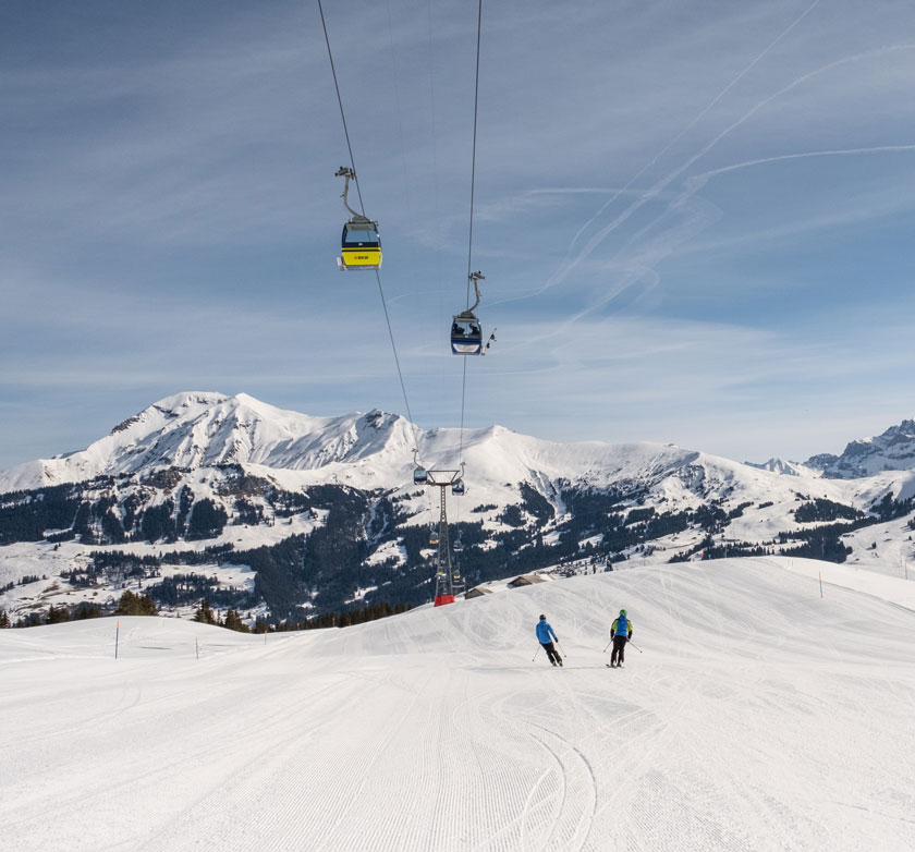 Winter scene at Betelberg in Switzerland, featuring a bustling ski resort with a ski lift in operation. Skiers glide down the snow-covered slopes near a cozy challet.
