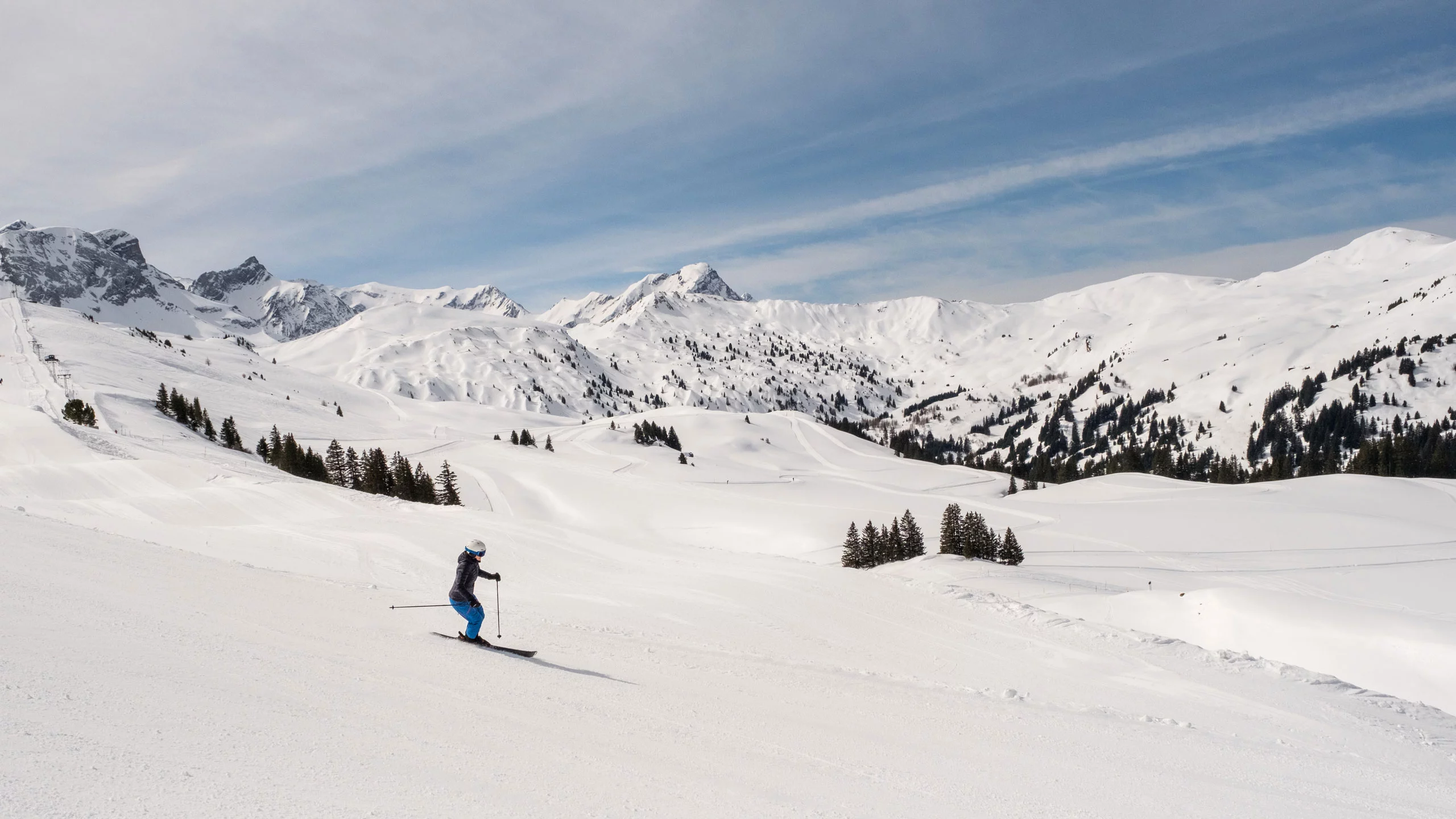 A skier gliding down the snowy slopes of Betelberg in Bernese Oberland, Switzerland, with a cozy chalet and the bustling ski resort in the background.
