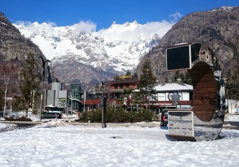 Chalet and ski resort at Mont Blanc, Courmayeur, Italy amidst a stunning winter scene with snow-covered mountains as the backdrop.