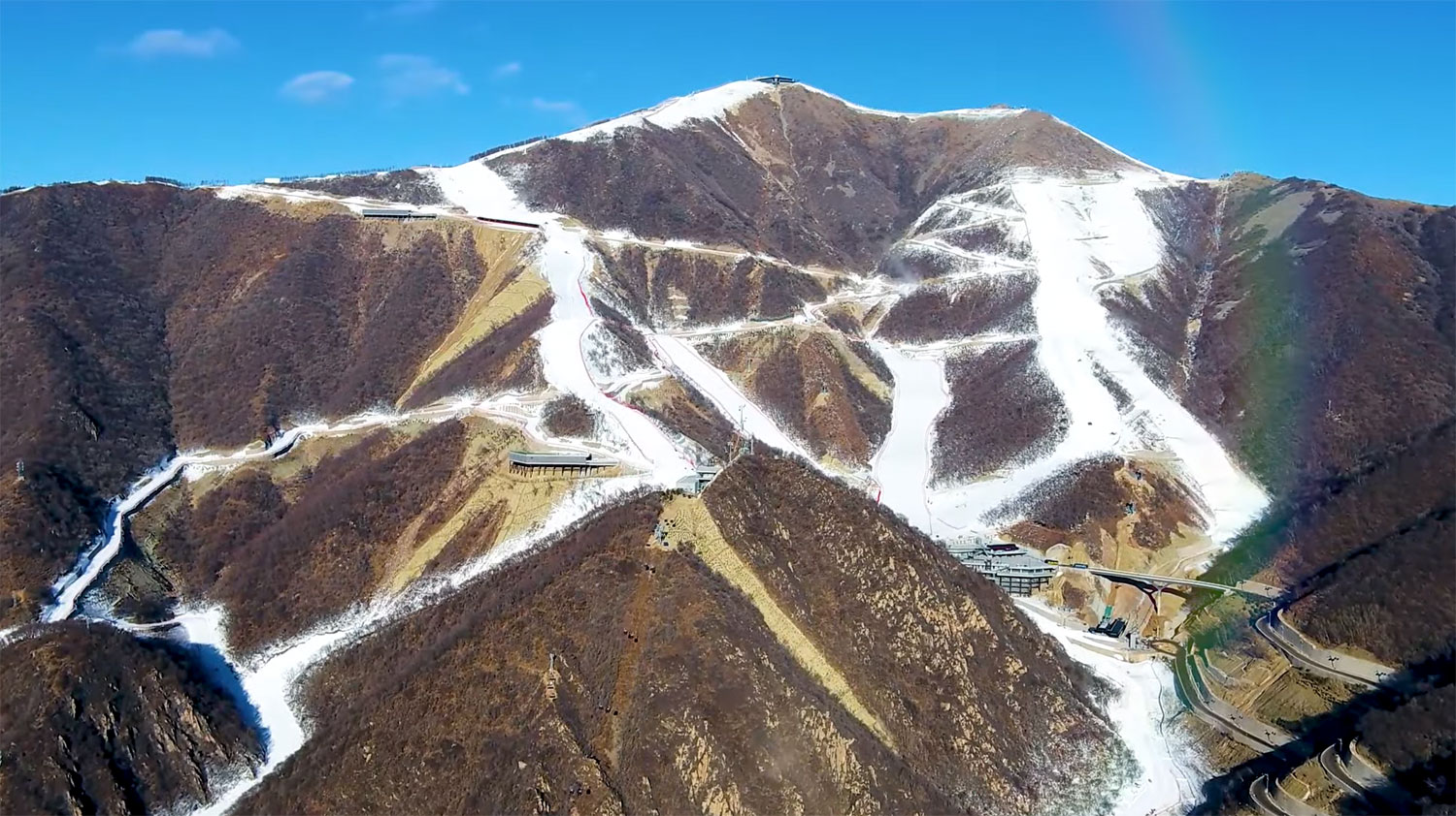 Yanqing National Alpine Ski Centre in China - a rainbow in the sky over a mountain.