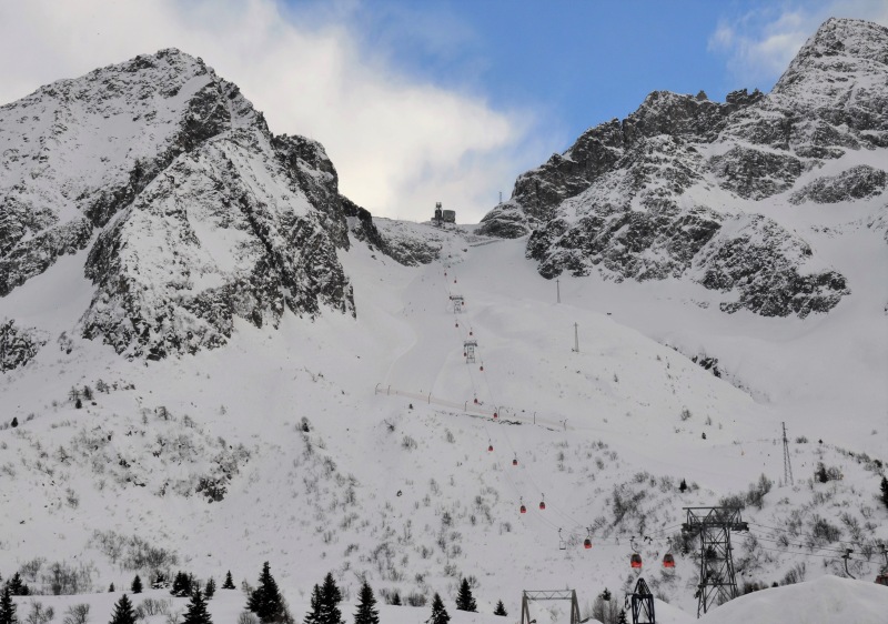 A picturesque chalet scene at the Consorzio Pontedilegno-Tonale ski resort in Trentino-Alto Adige Italy. Winter sports enthusiasts take advantage of the snowy conditions under a ski lift.
