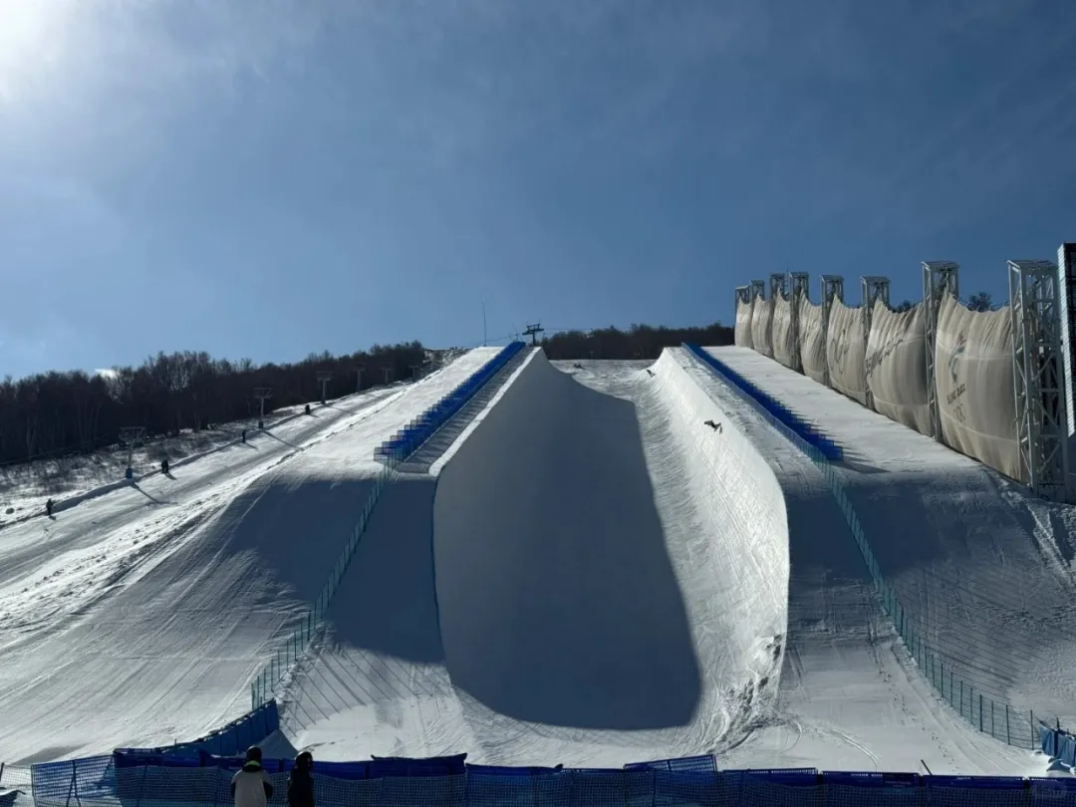Thaiwoo Ski Resort in China - a snowboarder is going down the side of a hill.