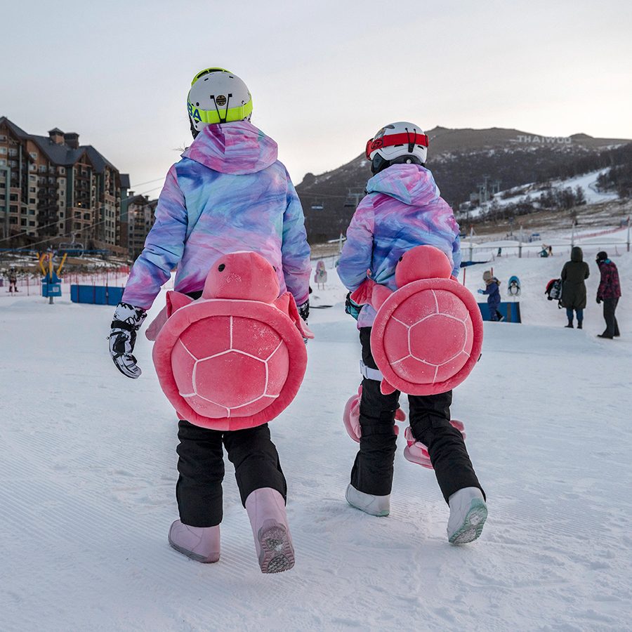 Thaiwoo Ski Resort in China - two people walking in the snow carrying snowboards.