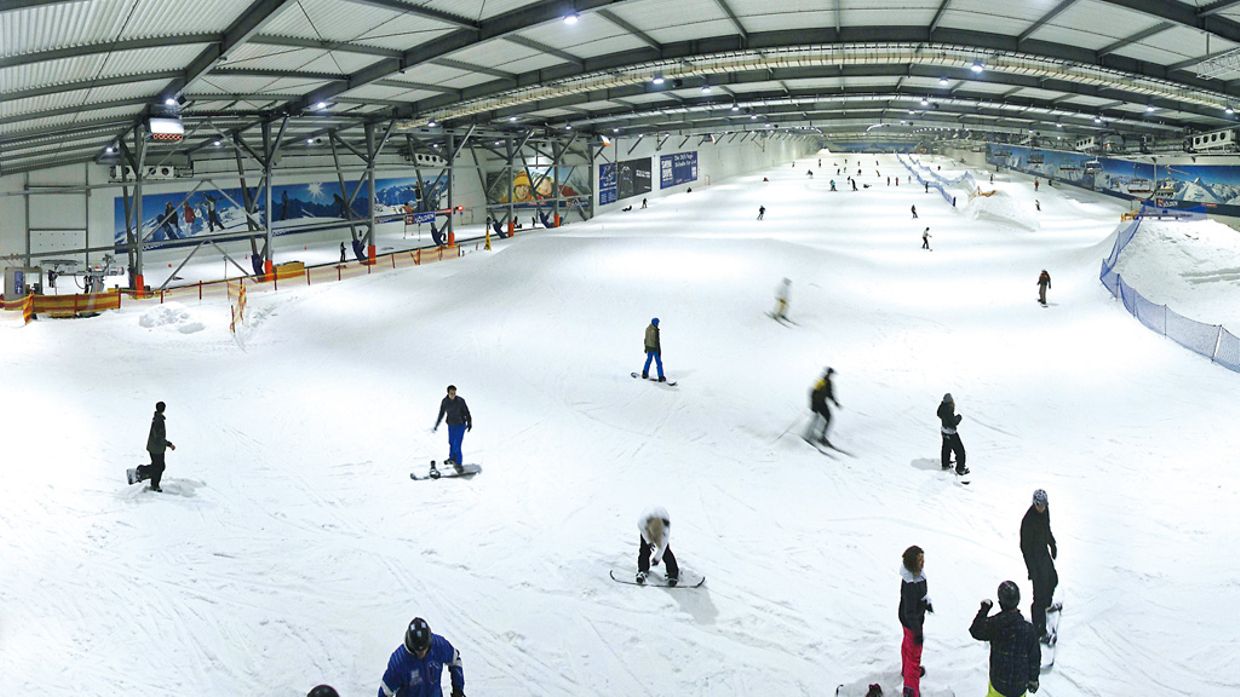 Snow Dome Bispingen in Germany - a group of people skiing down a snowy slope.