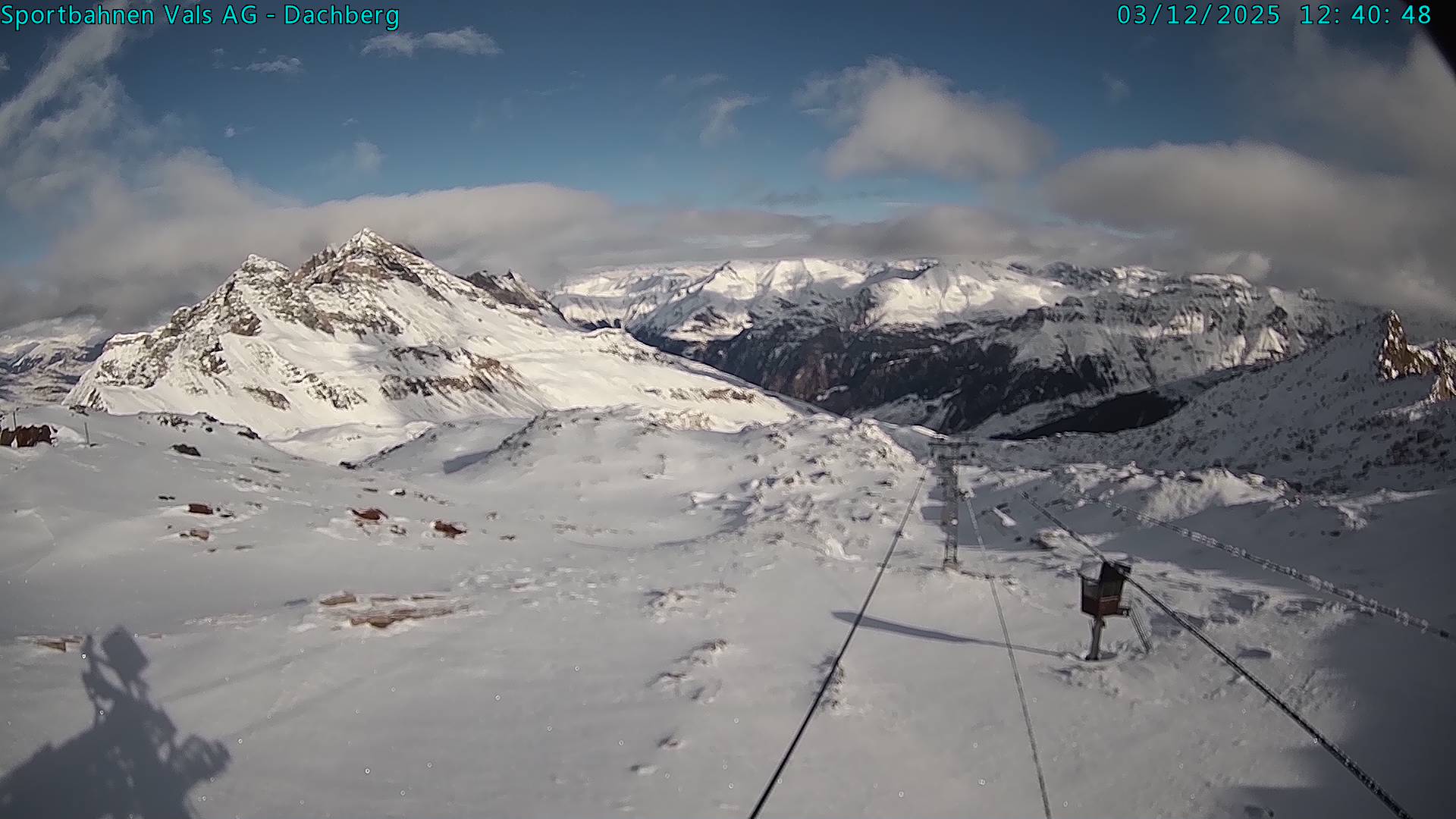 A picturesque view of Vals-Dachberg in Eastern Switzerland featuring a charming chalet, ski lift, and a skier effortlessly gliding downhill amid the bustling winter sports scene at the ski resort.