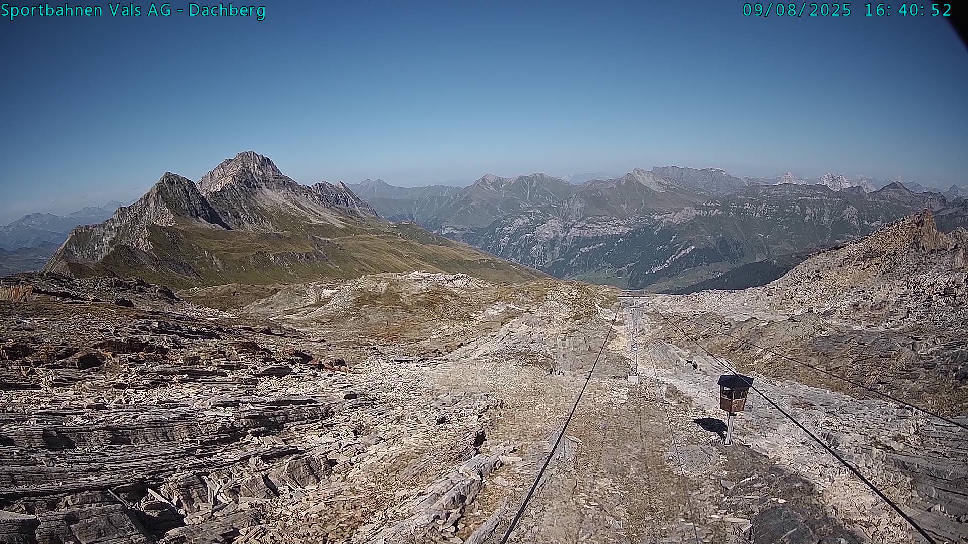 A picturesque view of Vals-Dachberg in Eastern Switzerland featuring a charming chalet, ski lift, and a skier effortlessly gliding downhill amid the bustling winter sports scene at the ski resort.