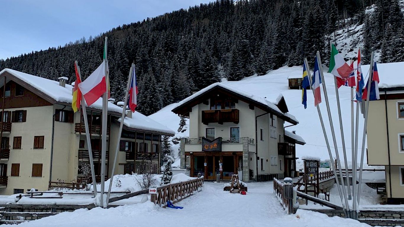 Santa Caterina Valfurva in Italy: a snow covered area with several buildings and flags.