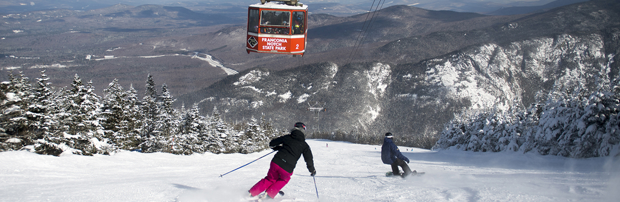 Cannon Mountain in USA - two people skiing down a mountain.