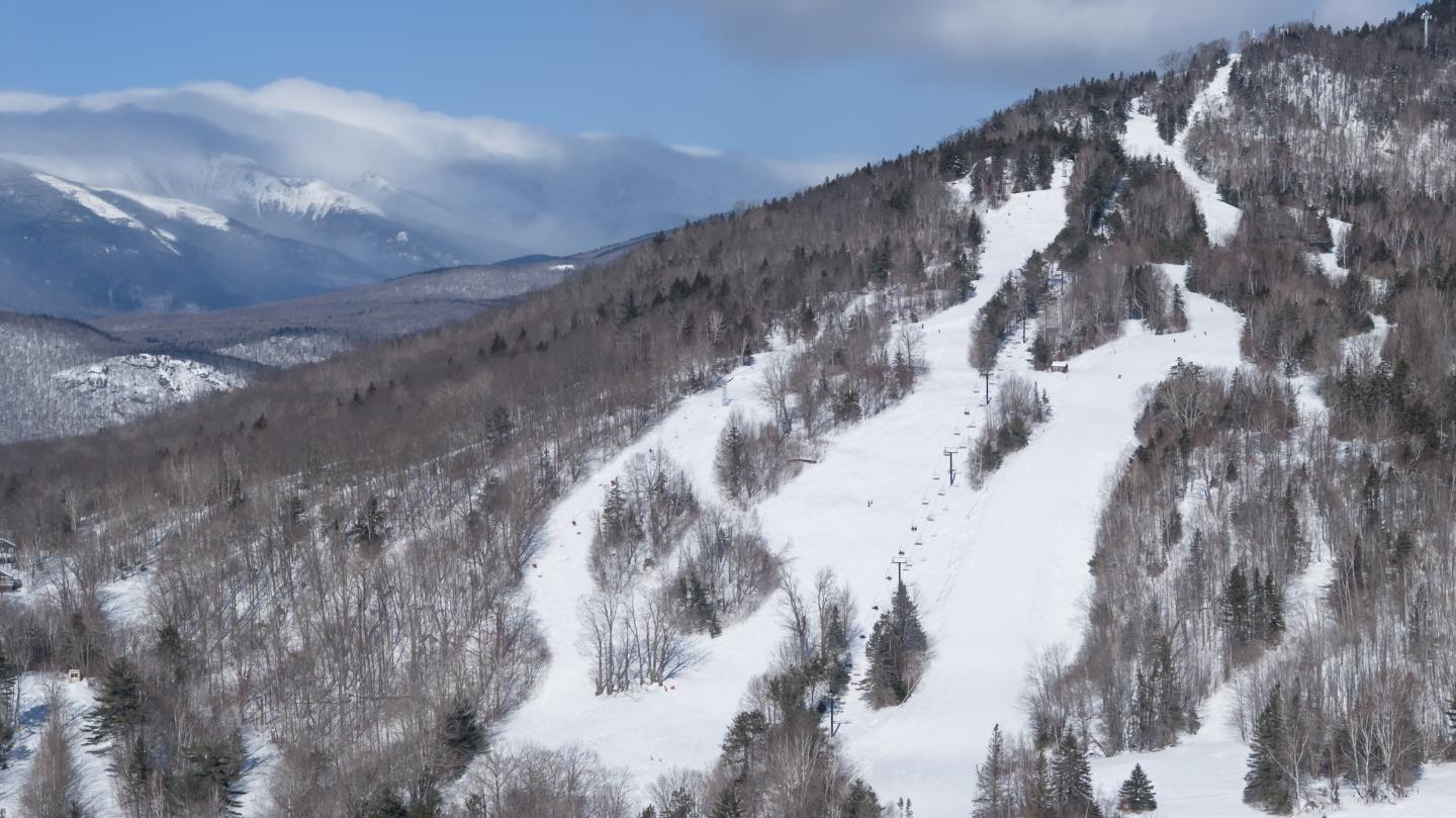 Cannon Mountain in USA - a snowy slope with trees and mountains in the background.
