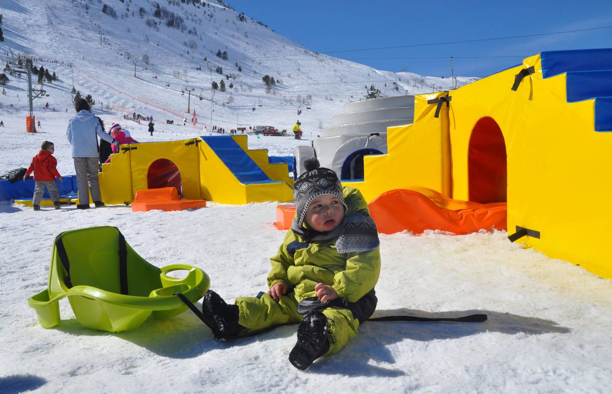 Porté Puymorens in France - a young boy sits on the snow in front of his tent.