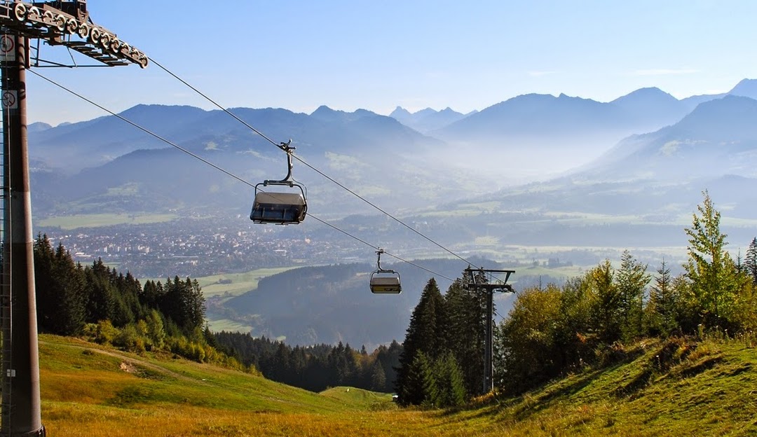 Bergbahnen Ofterschwang- Gunzesried GmbH & Co. KG in Germany - a ski lift going up a hill with mountains in the background.