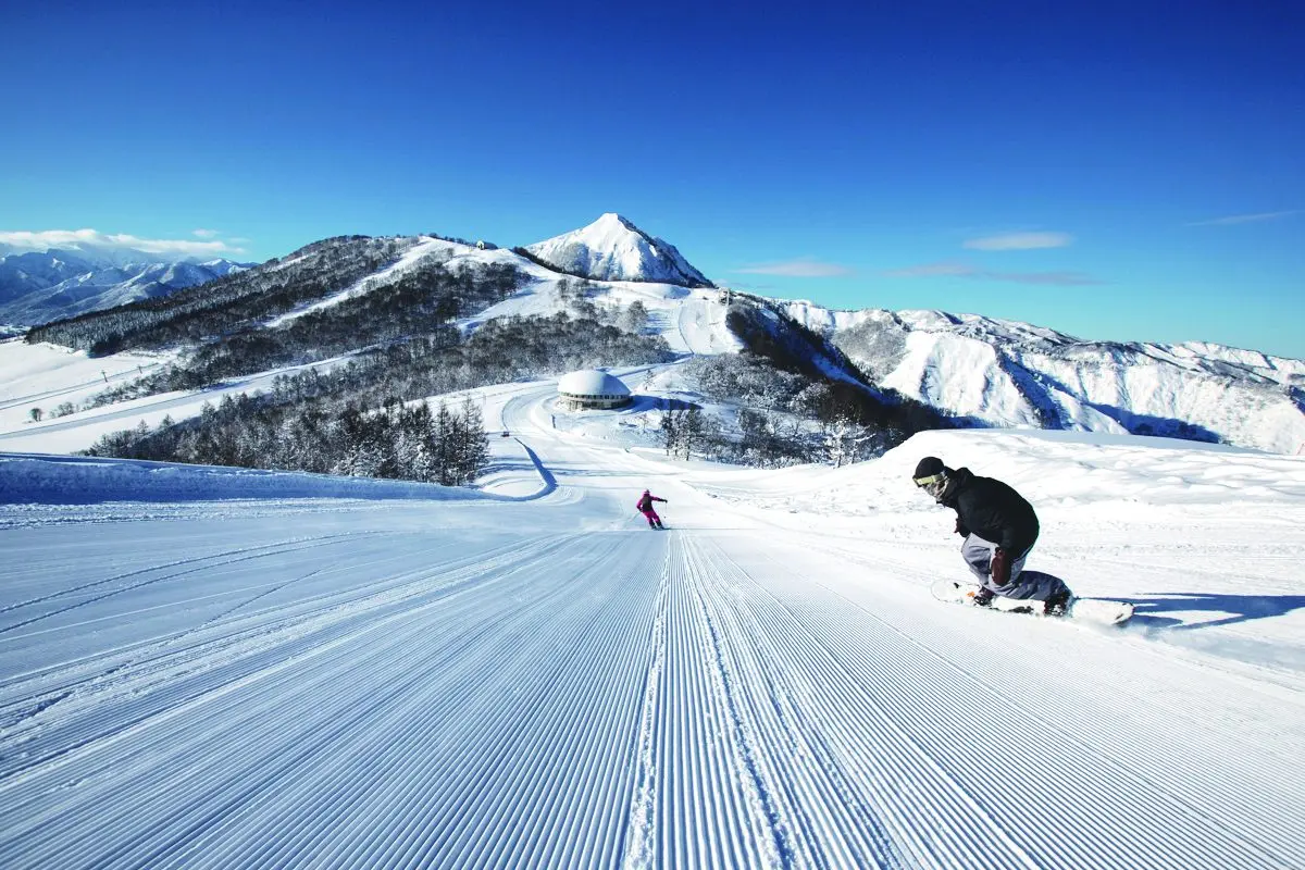 Maiko Snow Resort in Japan - a person riding a snowboard down a snow covered slope.