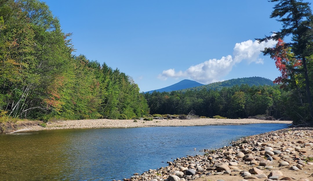 Attitash Mountain Resort in USA - a river with rocks and trees in the background.