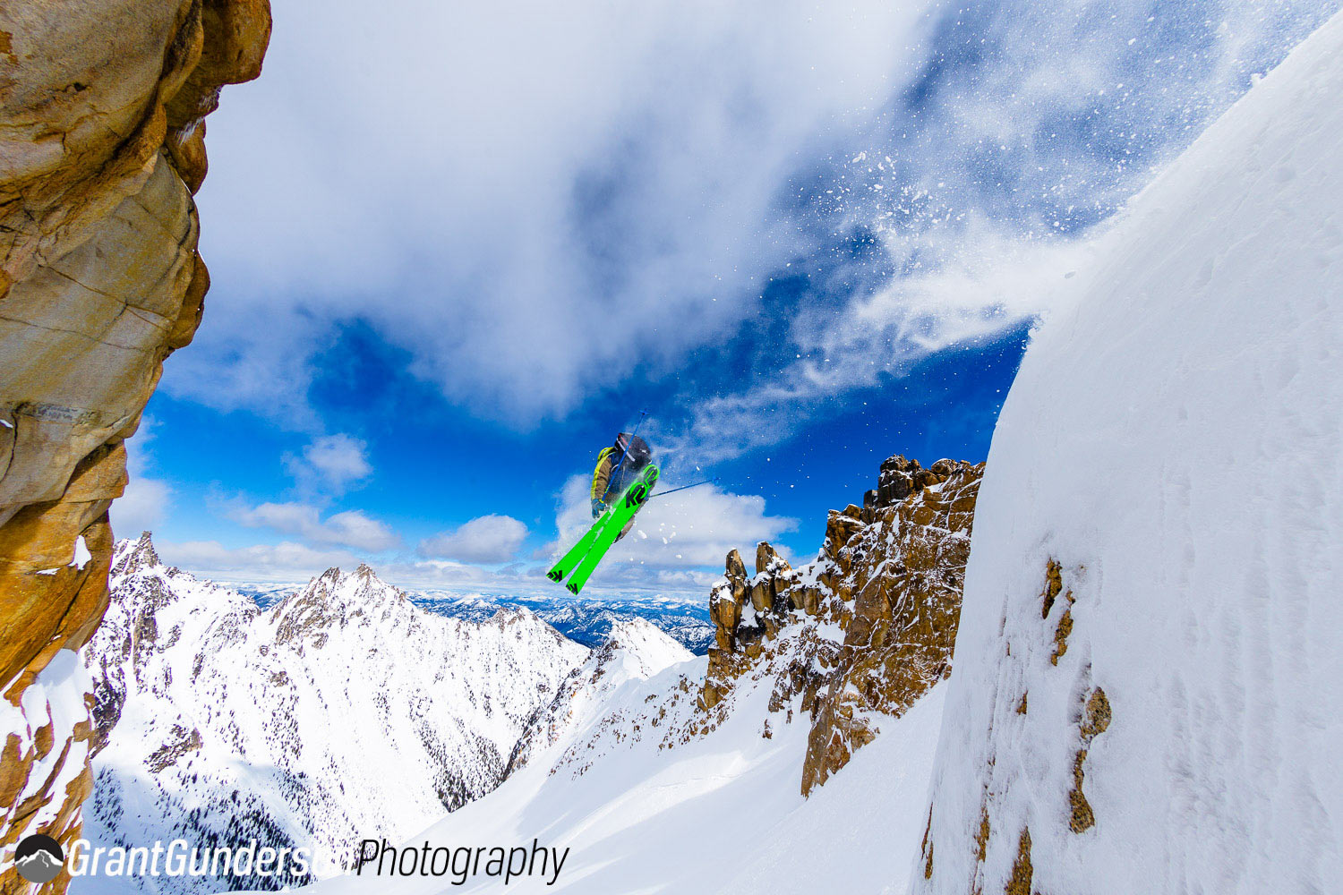 North Cascade Heliskiing – Mazama in USA - a person on a snowboard jumping off of a cliff.