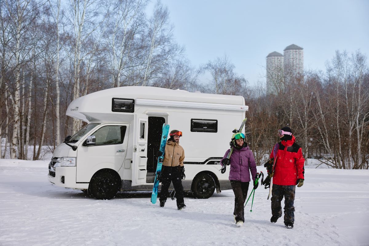 Hoshino Resorts Tomamu in Japan - two people standing next to a camper van in the snow.