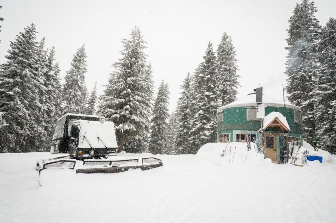 Cascade Powder Guides in USA - a snowmobile parked in the snow in front of trees.