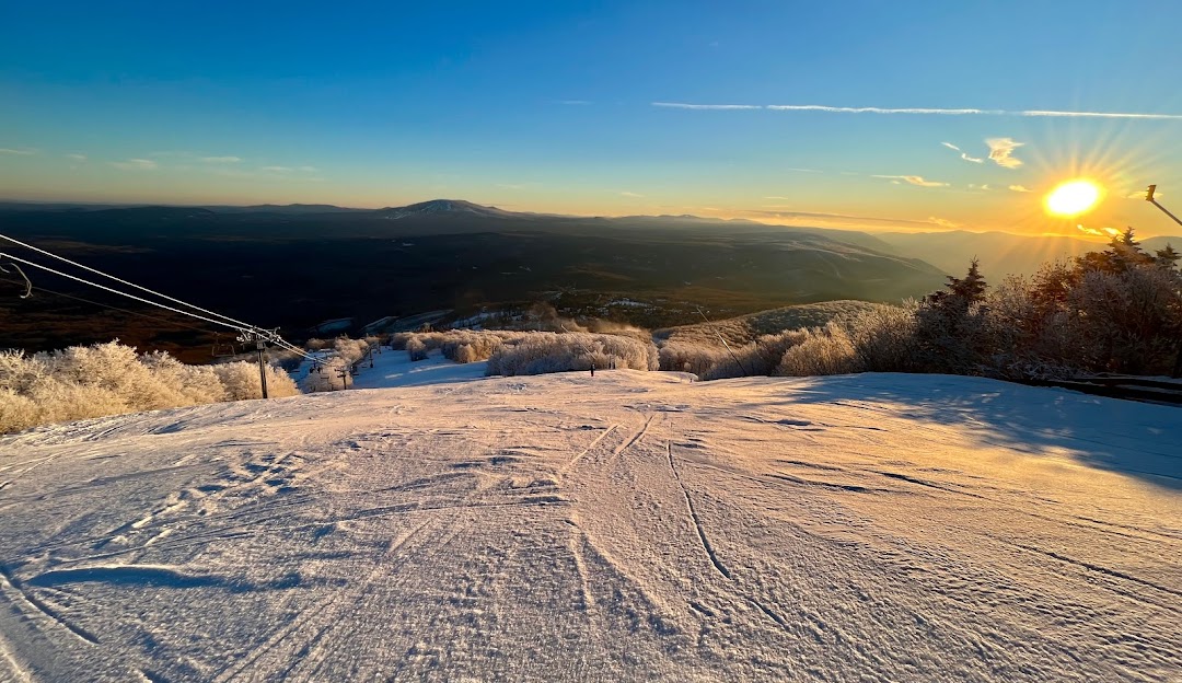 Bromley Mountain in USA - a snow covered ski slope with the sun in the background.