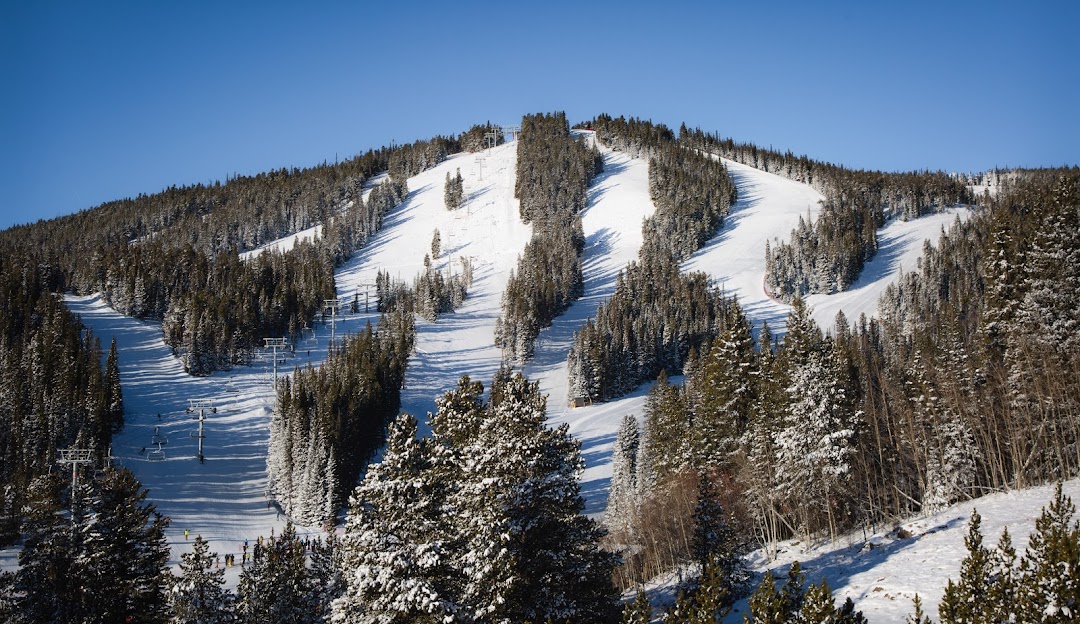 Eldora Mountain in USA - a snow covered mountain with trees and a blue sky.