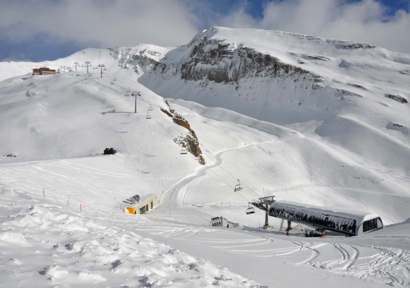 A scenic view of the Leukerbad ski resort in Switzerland highlighting a quaint chalet and snow-covered slopes bustling with winter sports activities.