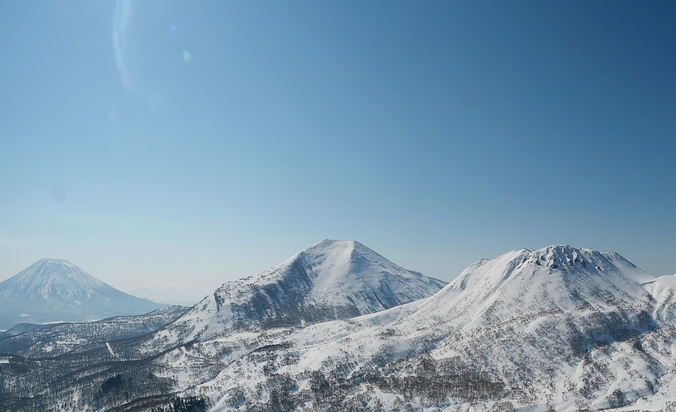 View of Niseko Weiss Cat Ski resort in Hokkaido, Japan featuring a stunning snow-capped mountain surrounded by a picturesque winter landscape, with a bustling winter sports scene in progress.