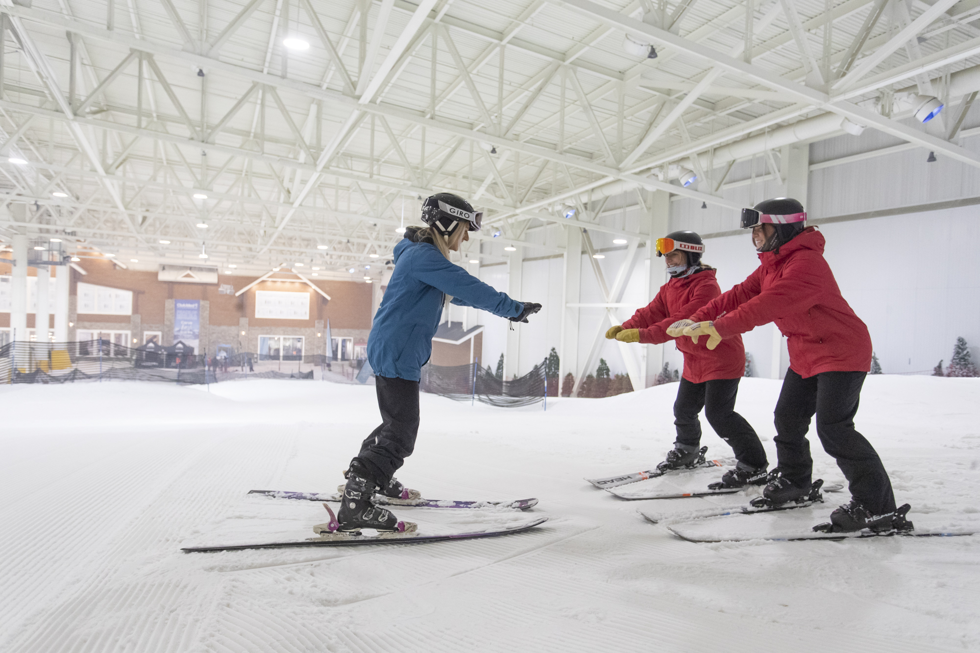 A winter sports scene at Big Snow American Dream in New Jersey, USA showcasing a group of people and a family enjoying skiing at the indoor ski resort.