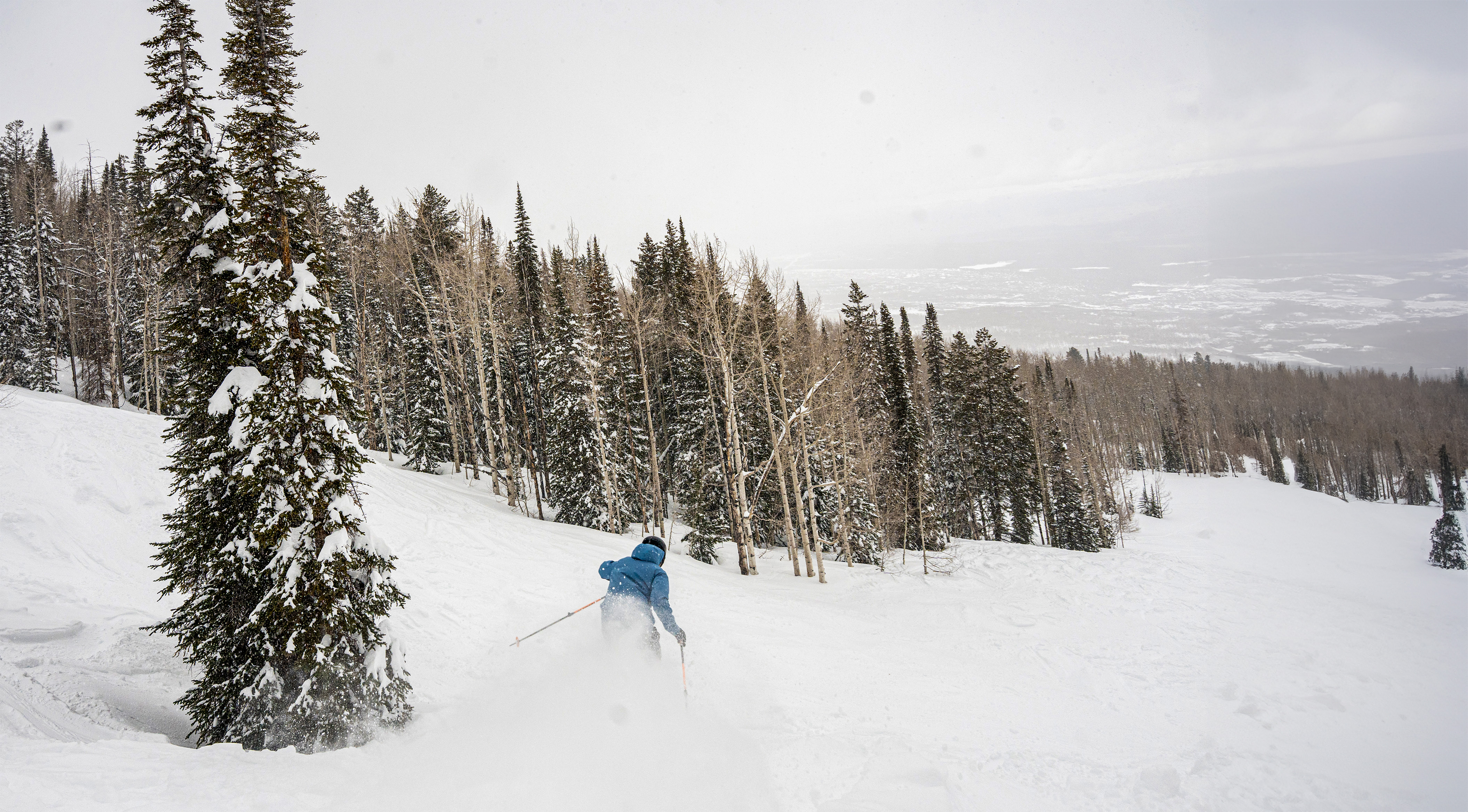 A skier and snowboarder enjoying winter sports at the Powderhorn ski resort in Colorado USA with a ski lift operating in the background.