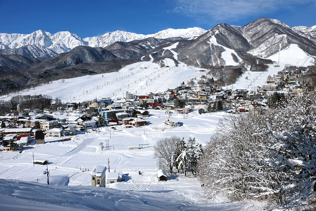 Tsugaike Kogen in Japan - a view of a snowy town with mountains in the background.