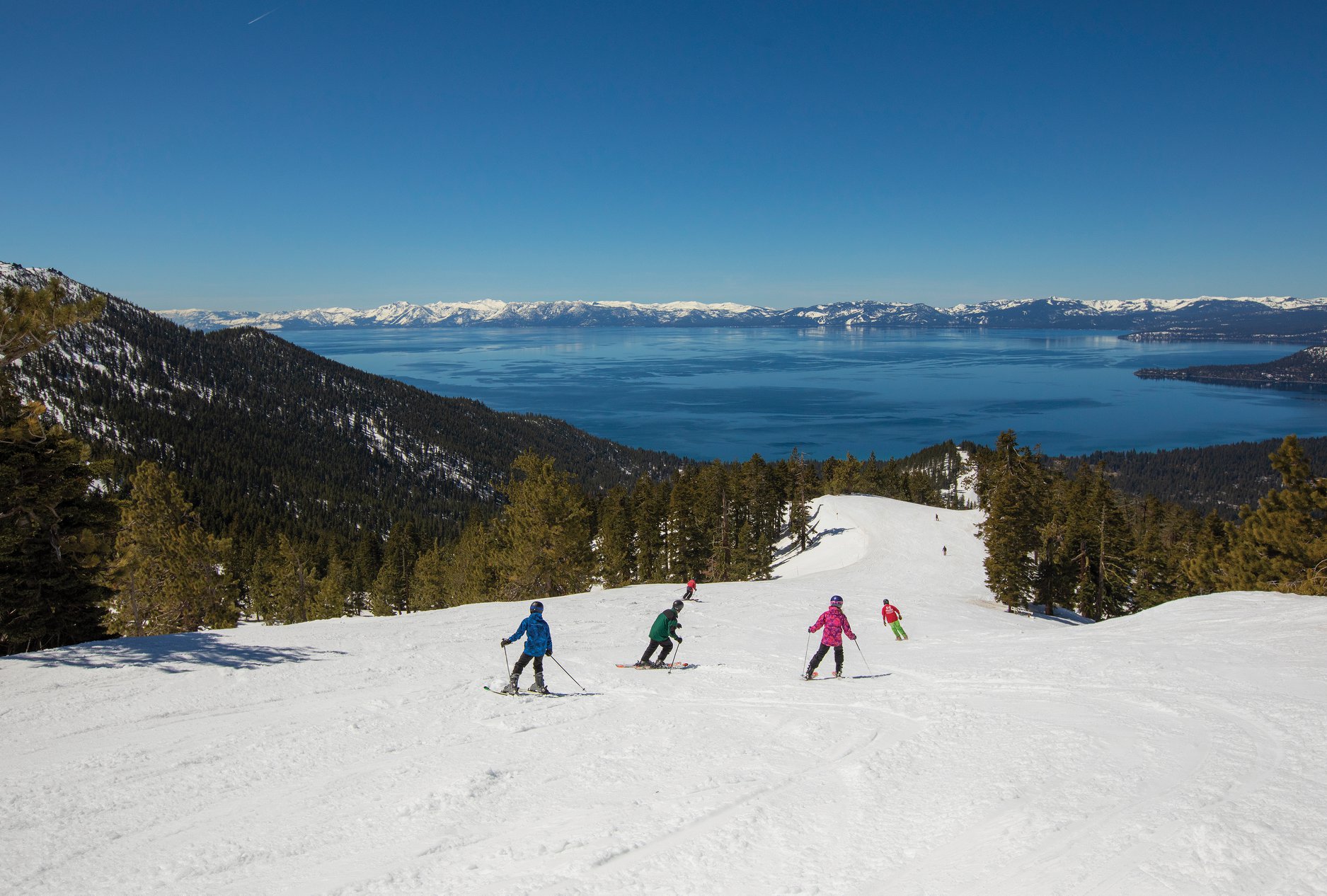 A lively winter scene at Diamond Peaks Utah showing a group of people engrossed in skiing activities with a bustling ski resort in the backdrop.