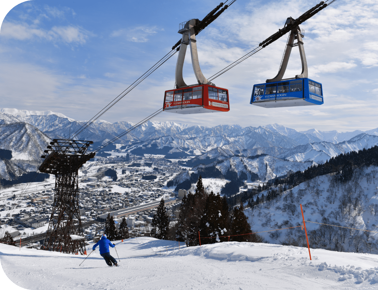Winter sports scene at Chūbu, Honshu, Japan, featuring a ski lift and chalet amidst the ski resort of Yuzawa Kogen | ​Gala Yuzawa | ​​Ishiuchi Maruyama with a skier apparent nearby.