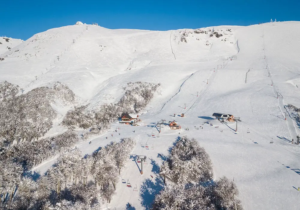 Scenic view of Chapelco Ski Resort in San Martín de los Andes, Argentina featuring striking winter landscape, bustling with winter sports enthusiasts.