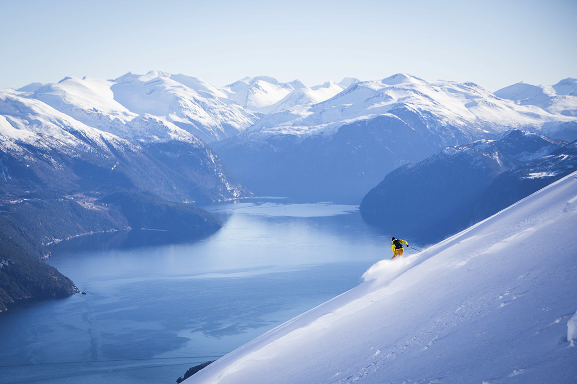 Strandafjellet Skisenter in Norway - a person skiing down a snowy slope with mountains in the background.