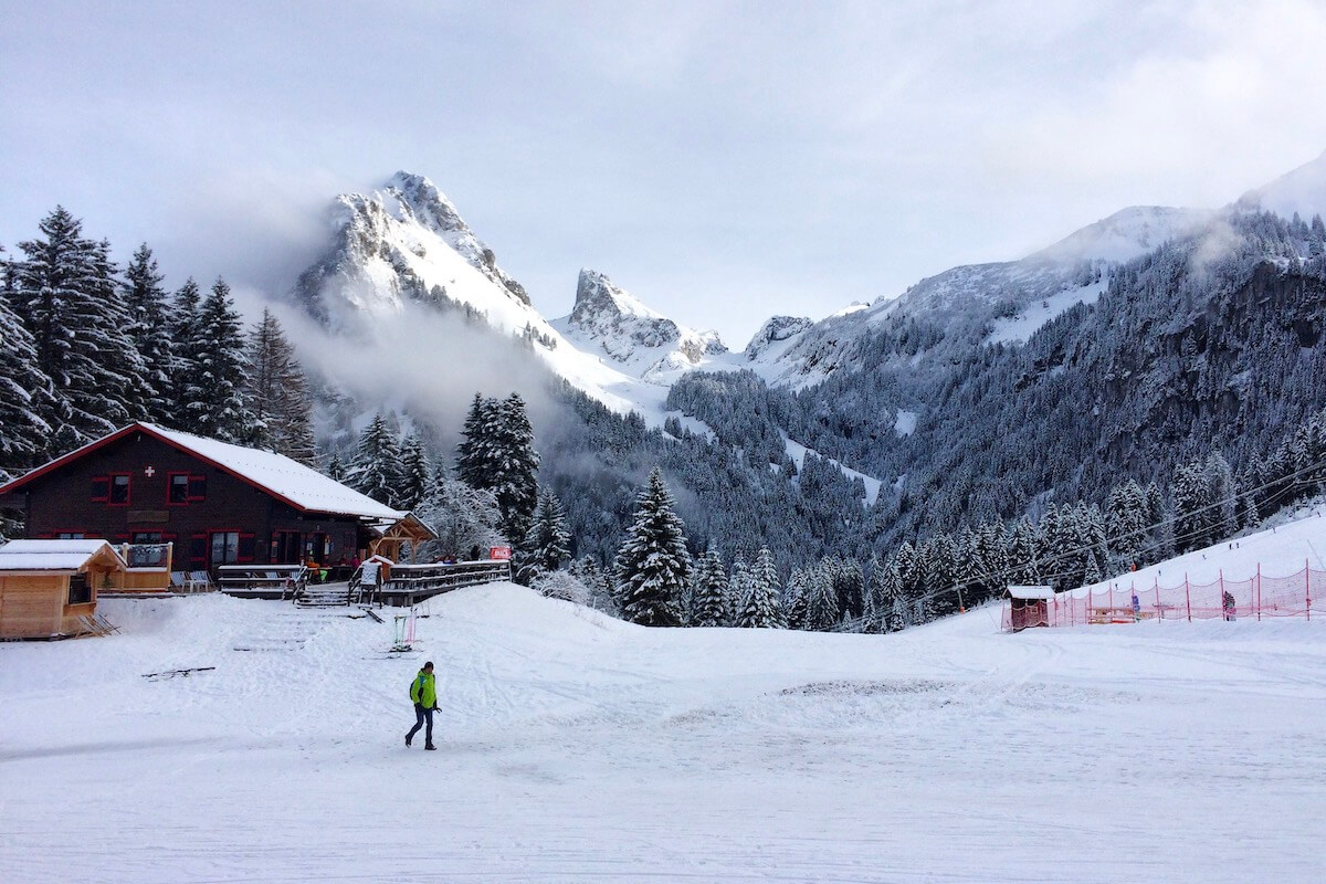 Thollon les Mémises in France - a person standing in the snow near a cabin.